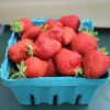 Bright red strawberries in small blue carton