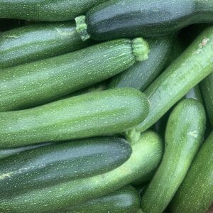 Fresh green zucchinis piled in wooden crate