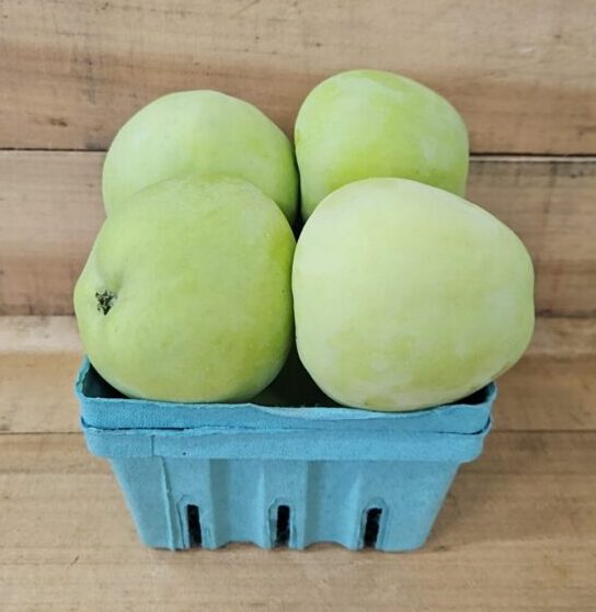 Four pale green apples in blue basket