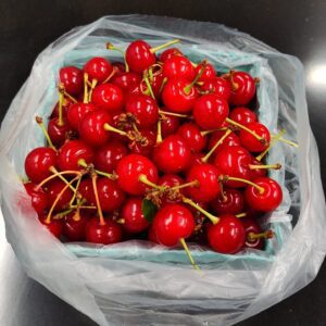 Container of glossy red cherries in bag