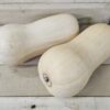 Two pale butternut squashes on wooden surface.