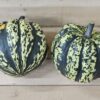 Two striped winter squashes on wooden surface.
