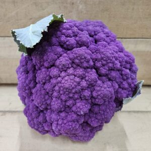 Purple cauliflower head with green leaves